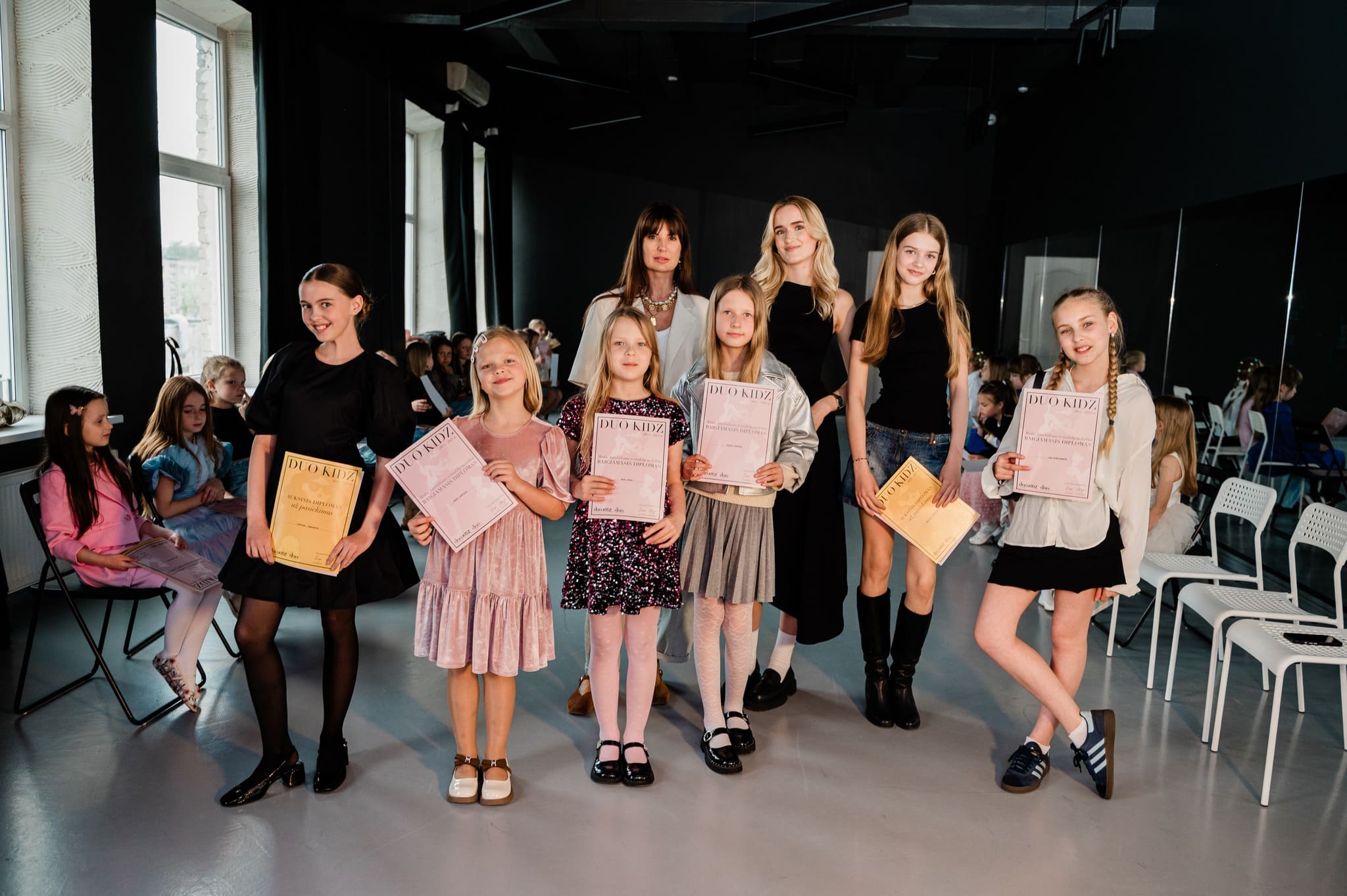 Duo Kidz modelių mokyklos būrelio mokinės mokslo metų užbaigimo renginyje, švenčiančios pasiekimus ir augimą.